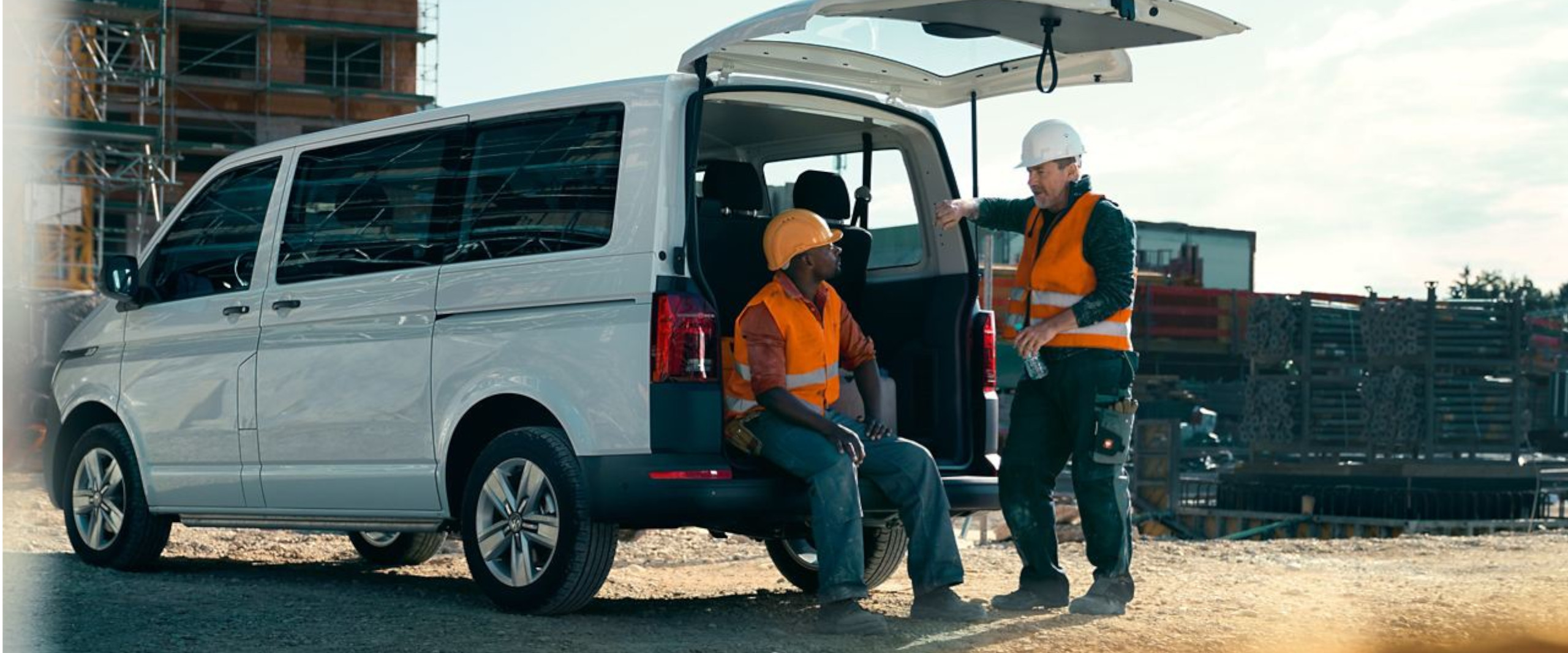 zwei Männer in Bauarbeiteruniform unterhalten sich am VW Transporter Kombi